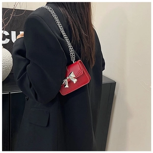 Red mini crossbody bag featuring a shiny silver metal bow and fine metal chain strap