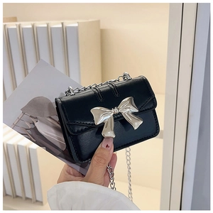 Detail of black mini square bag featuring silver bow metal buckle and chain strap