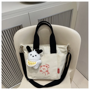 Detail of canvas tote with cute bear print and plush bunny charm on white chair