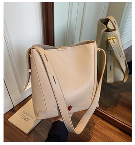 Detail of beige litchi grain leather bucket bag with wide adjustable shoulder strap