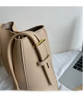 Close-up of litchi grain texture on apricot bucket bag with gold T-shaped buckle