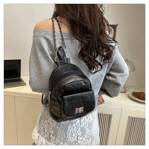 Macro detail of black quilted leather mini backpack with metal chain strap and turn-lock