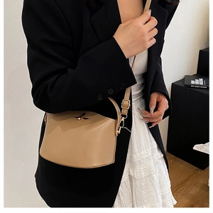 Detailed view of khaki leather crossbody bag with a golden twist lock and adjustable strap