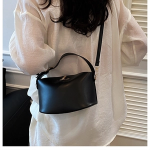 Detail view of the black minimalist bucket bag with golden hardware and adjustable strap
