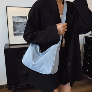 Light blue crescent hobo crossbody bag worn by a model in a modern interior setting