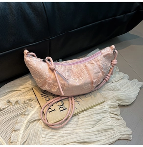 Dettaglio della borsa a mezzaluna rosa con ricamo a farfalla e design del manico a nodo
