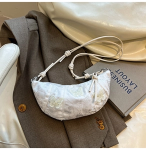 Detail of white crescent bag with 3D butterfly embroidery and knotted rope strap