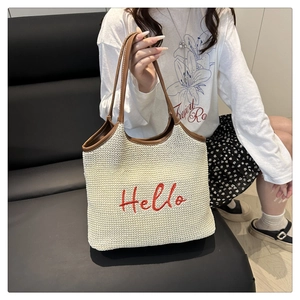 Detail of red Hello embroidery on off-white knit tote bag with brown leather handles