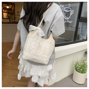 Detail of beige lace tote bag featuring intricate crochet patterns and a large white bow