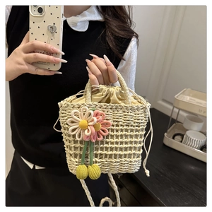 Detail of hand-woven straw crossbody bag with floral charm and drawstring lining