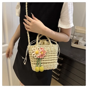 Detail of hollow woven straw bag with colorful floral charms and drawstring inner