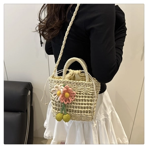 Detail of straw bucket bag featuring knitted daisies and cherries with drawstring closure