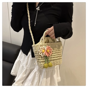 Detail of straw bucket bag with floral decor, shoulder strap and drawstring lining