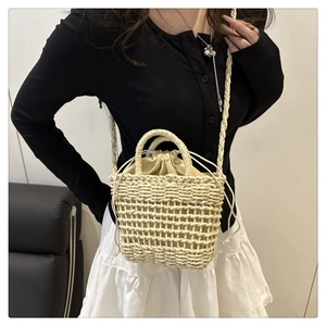 Detail of hollow-out woven straw bag featuring drawstring lining and long shoulder strap