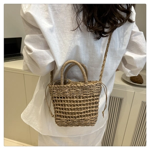 Mini hand-woven straw bag with drawstring liner and crossbody strap shown on a model