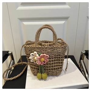 Detail of straw woven bucket bag with handmade fabric flowers and drawstring liner