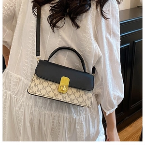 Detailed view of bicolor crossbody bag with golden clasp and all-over letter pattern