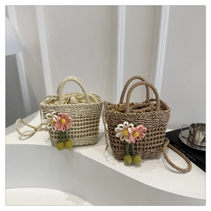 Detail of hand-woven straw bucket bags with floral charms and drawstring liners
