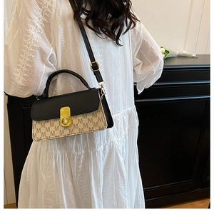 Detailed view of bicolor square bag with M-letter prints and gold twist lock closure