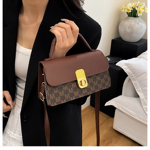 Detail of the vintage-style flap square bag with monogram pattern and gold metal twist lock