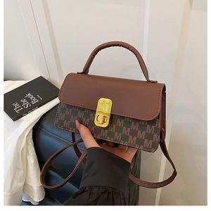 Close-up of contrast letter print bag with gold metal twist lock and brown handle