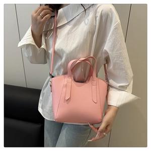 Close-up of pink litchi grain leather bucket bag featuring a detachable crossbody strap