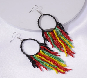 Detail of bohemian round beaded hoop earrings with vibrant red yellow and green tassels