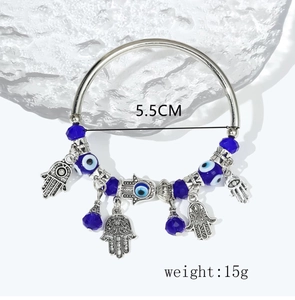 Detail showing Evil Eye and Hamsa Hand charms on a 5.5cm silver-tone bangle