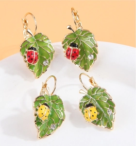 Détail des boucles d'oreilles en forme de feuille avec émail vert et coccinelle