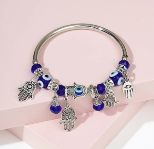 Detailed close-up of Hamsa Hand charms and Evil Eye beads on a silver-tone bangle