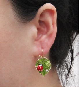 Détail de boucles d'oreilles coccinelle sur feuille verte avec nervures dorées et cristal