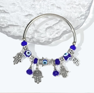 Detail of silver bangle with Hamsa Hand pendant and blue Evil Eye beads on ice base