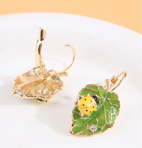 Vue détaillée de boucles d'oreilles feuille verte avec petit coccinelle jaune