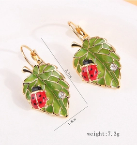 Détail des boucles d'oreilles coccinelle sur feuille verte avec dimensions et zircon