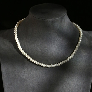 Classic single strand round pearl necklace displayed on a black neck mannequin stand