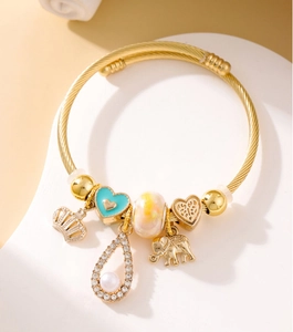 Detail of a gold-plated bangle featuring charms like an elephant, crown, and glass beads