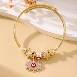 Detailed view of golden twisted bangle featuring evil eye charm and rhinestone star accents