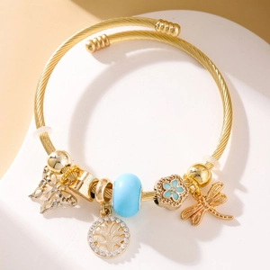 Detail of a golden wire bracelet featuring butterfly, life tree, and dragonfly charms