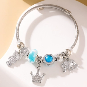 Detail view of a silver-tone cable bracelet with elephant, crown, and owl charms