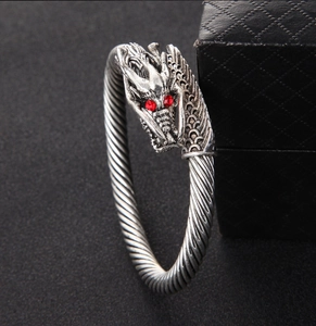 Close-up of vintage dragon head bracelet with red gemstone eyes and twisted metal band