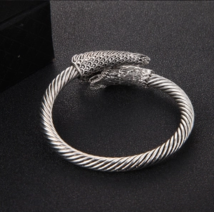 Close-up of vintage silver open cuff bracelet with detailed dragon head carvings