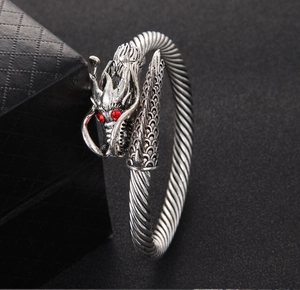 Detailed close-up of retro silver dragon bracelet with red crystal eyes and twisted wire band