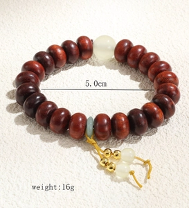 Détail d'un bracelet en perles de bois avec gland jaune et petit pendentif anneau vert