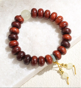 Détails d'un bracelet ethnique en perles de bois avec pierre de jade sur surface en pierre blanche