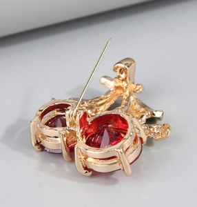 Detail of cherry brooch back showing gold alloy structure and secure safety pin fastener