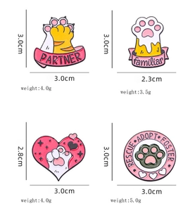 Detail view of four cat paw enamel pins showing precise size dimensions and weights
