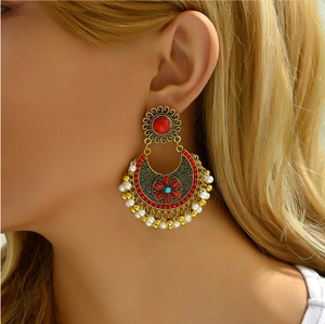 Detail of bohemian ethnic earrings with red stones and pearl tassels on a model