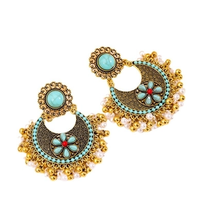 Ethnic bohemian drop earrings with turquoise stones and golden tassels on white backdrop