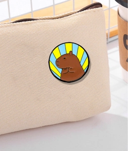 Vue détaillée d'une broche capybara en émail avec rayures radiales sur sac en toile