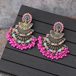 Detailed macro of bohemian peacock drop earrings with colorful enamel beads